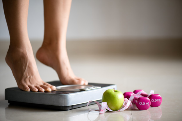 female-leg-stepping-weigh-scales-with-measuring-tape_53476-3874